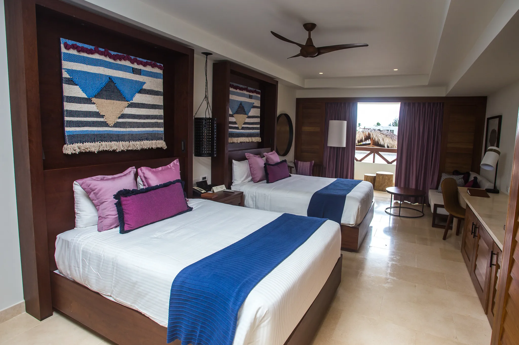 Preferred Club Junior Suite Tropical View with two double beds, seating area, and furnished balcony overlooking tropical scenery.