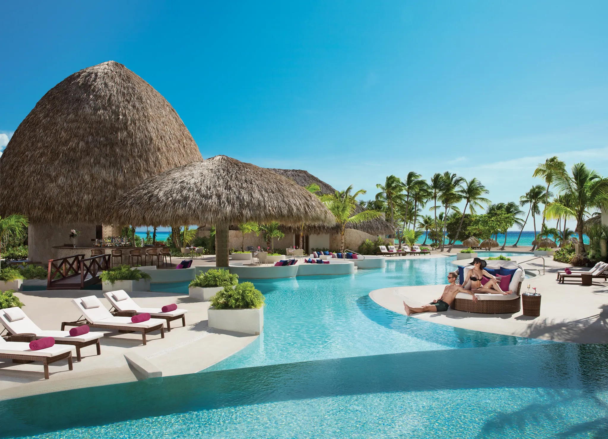 Guests relaxing beside the Preferred Club pool at Secrets Cap Cana Resort & Spa with swim-up access and tropical surroundings.