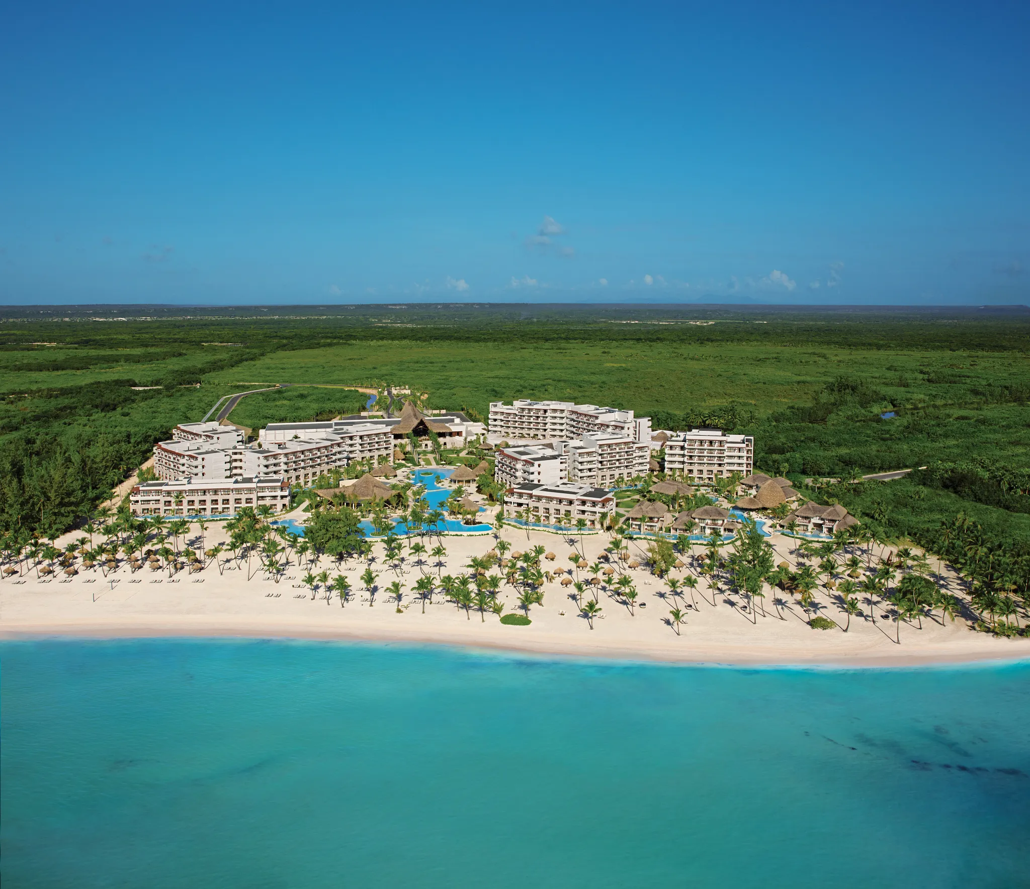 Aerial view of Secrets Cap Cana Resort & Spa situated along a pristine white-sand beach and turquoise Caribbean waters in Punta Cana.
