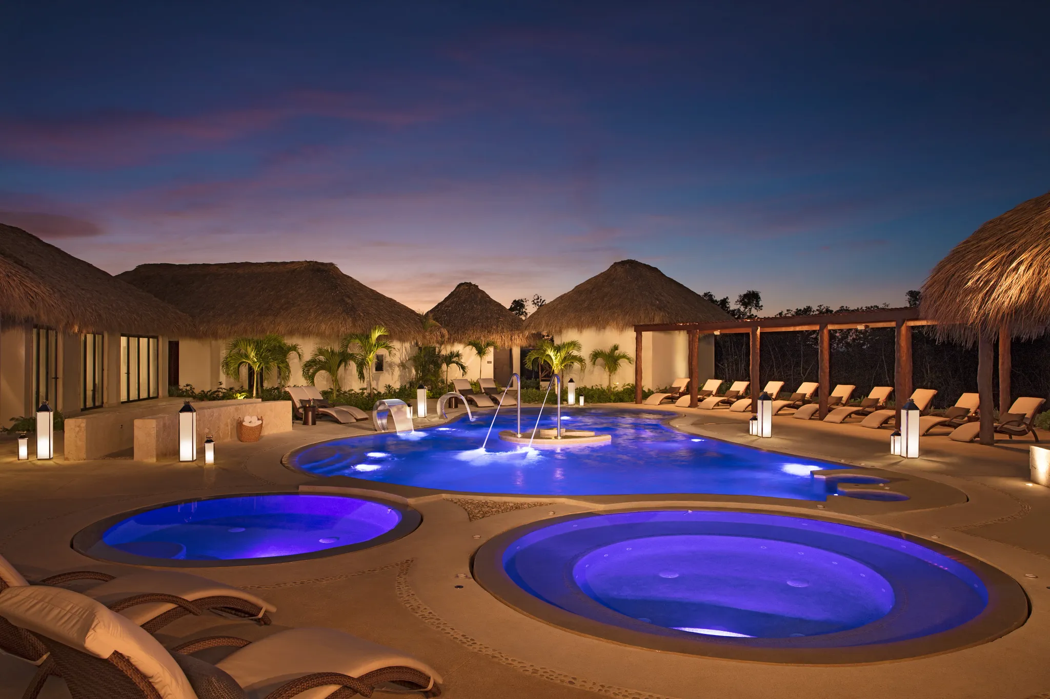 Illuminated hydrotherapy pools at night at Secrets Cap Cana Resort & Spa, creating a peaceful luxury spa atmosphere in Punta Cana.
